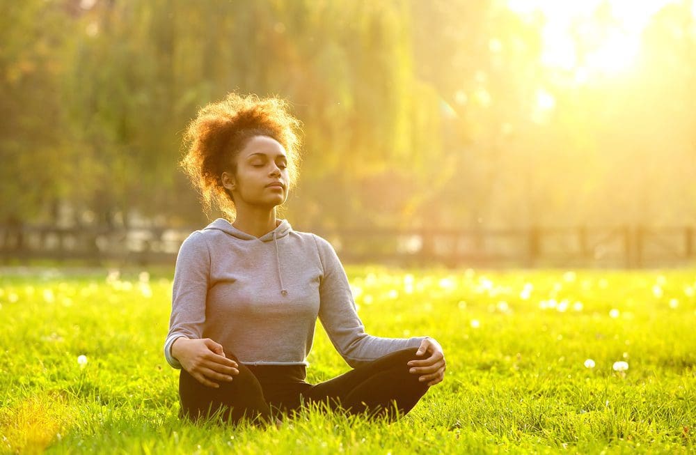 Woman meditating peacefully in a sunlit field